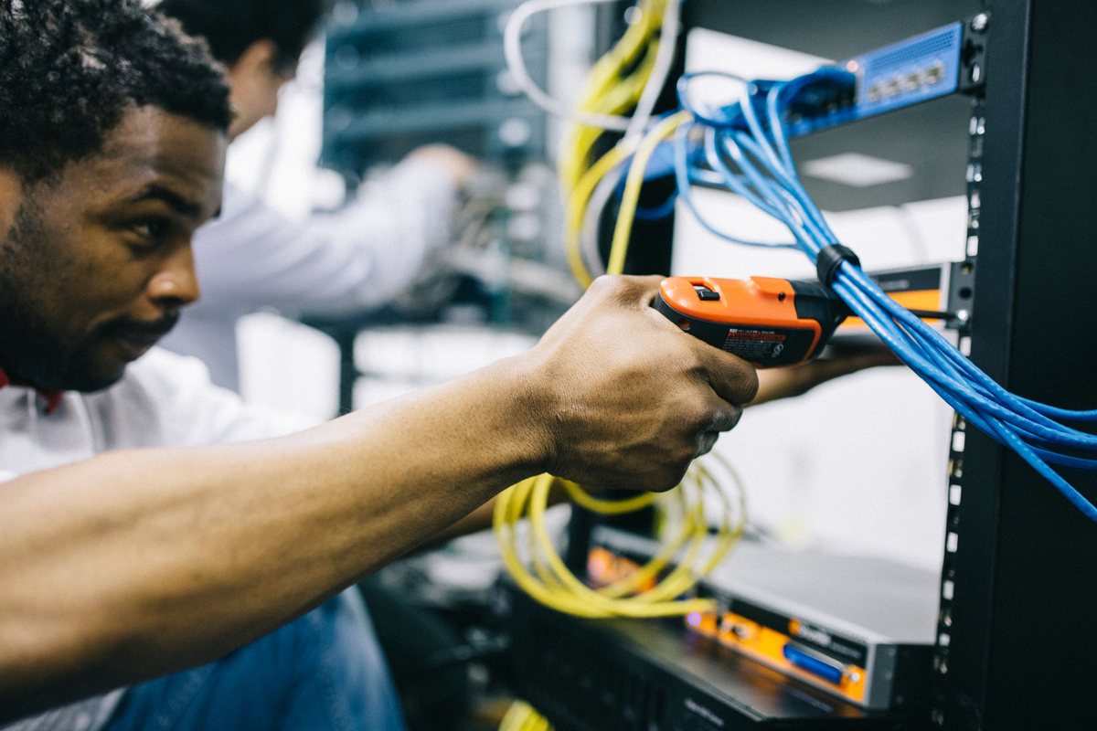 A technician fitting network cables into an equipment rack